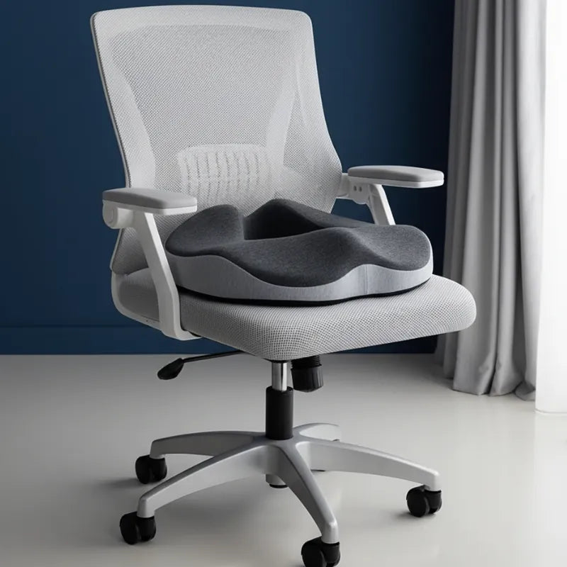 Coussin ergonomique noir et gris posé sur une chaise de bureau, présenté dans un décor premium