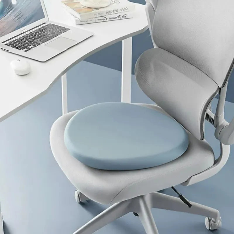 Coussin ergonomique rond bleu ciel sur une chaise de bureau moderne, utilisé pour un meilleur confort d’assise au poste de travail.