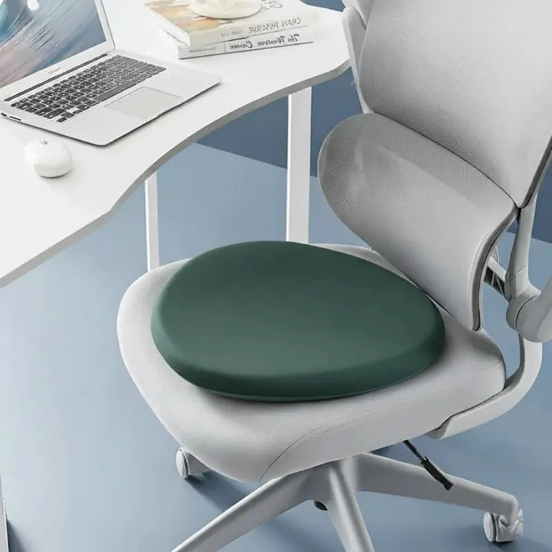 Coussin ergonomique rond vert foncé sur chaise de bureau design, conçu pour réduire la pression pendant les longues heures de travail.