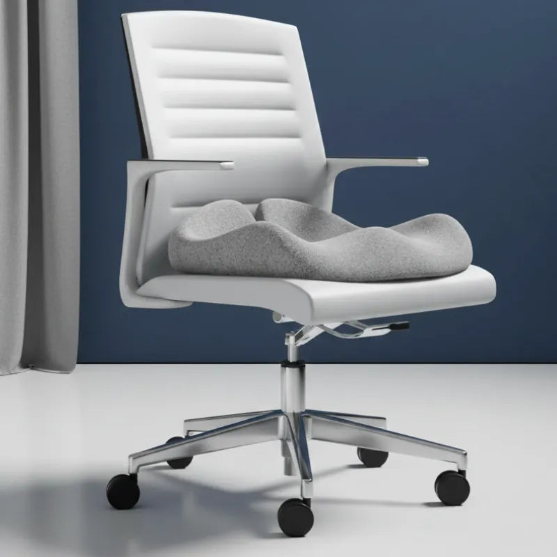 Coussin ergonomique pour fauteuil de bureau gris clair sur chaise de bureau blanche devant mur bleu
