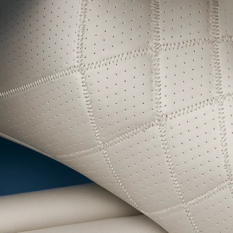 Zoom sur la texture du coussin ergonomique voiture beige en cuir synthétique perforé