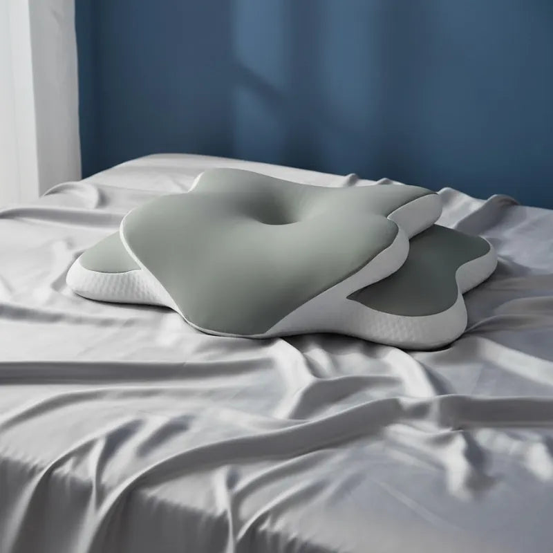 Oreiller mémoire de forme douleur cervicale vert 40x65cm posé sur un drap satiné gris perle devant un mur bleu profond