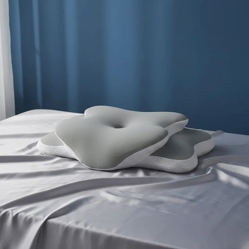 Oreiller memoire de forme douleur cervicale vert sur un drap gris perle légèrement plissé devant un mur bleu premium