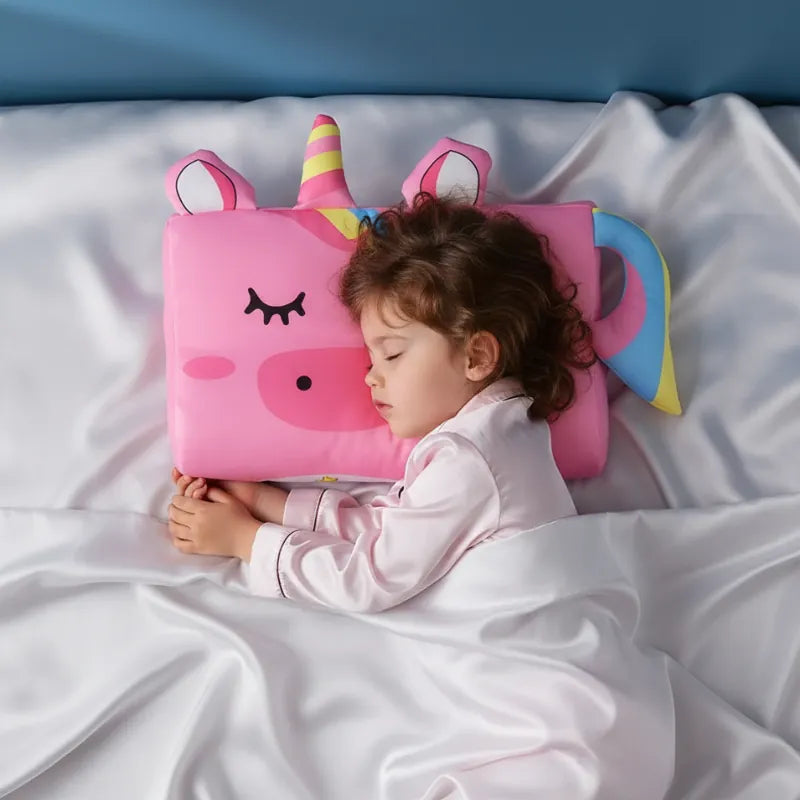 Enfant endormi paisiblement sur un oreiller mémoire de forme enfant licorne dans une ambiance douce et premium