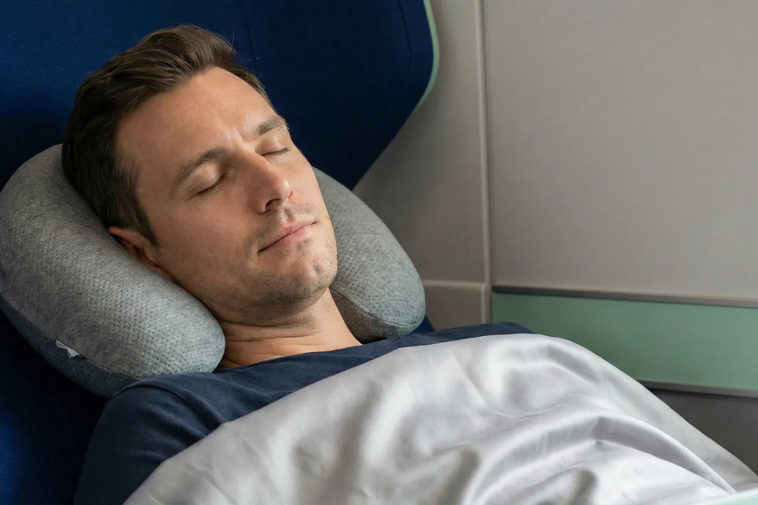 Coussin mémoire de forme de voyage soutenant la nuque d’un homme assis en avion, posture ergonomique et confort cervical