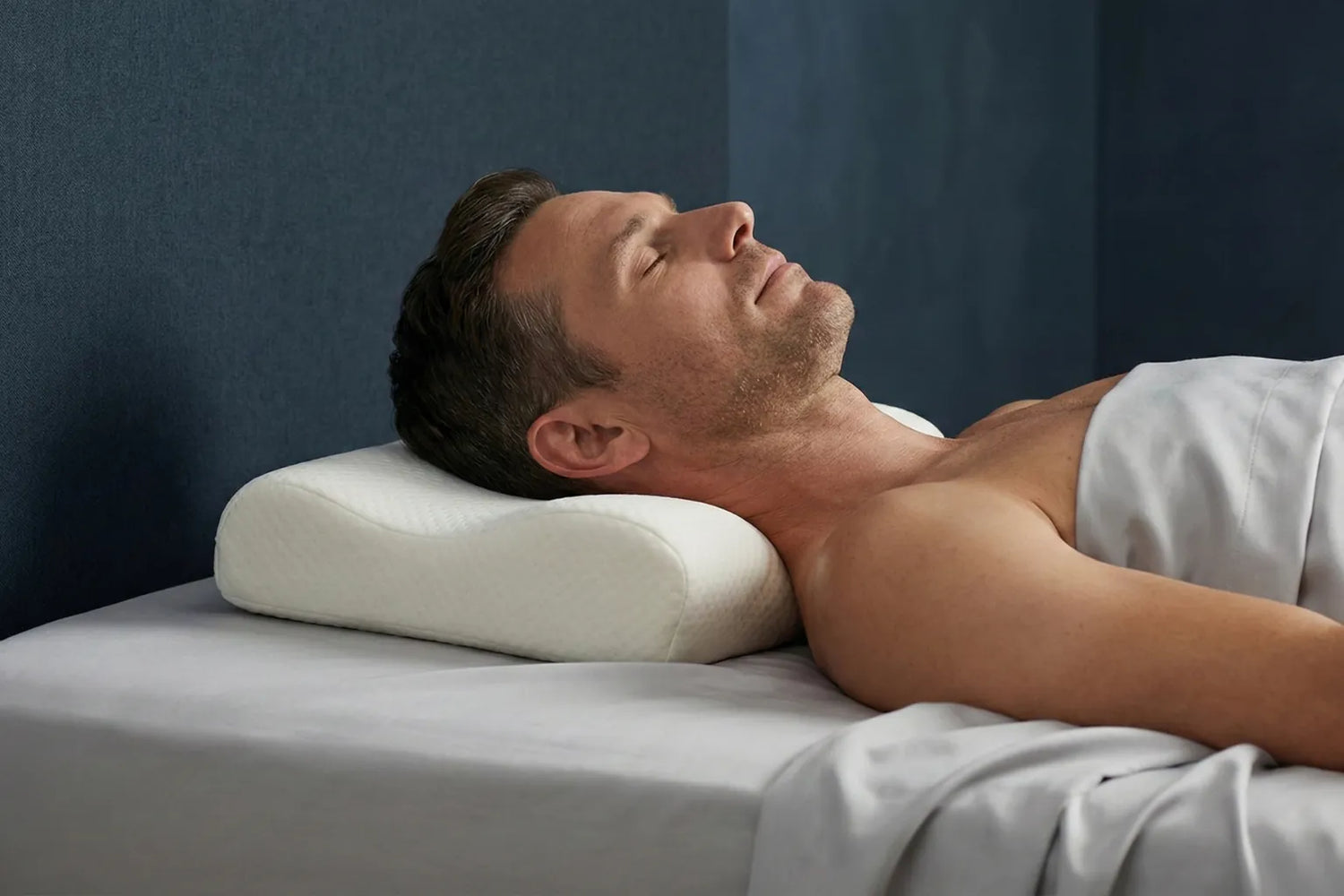 Homme dormant sur le côté avec un oreiller ergonomique favorisant l’alignement cervical et le soutien de la nuque