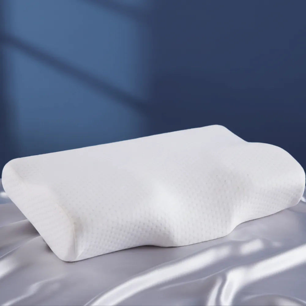 Oreiller 40x60 cm mémoire de forme blanc — coussin ergonomique en mousse viscoélastique, posé sur un drap satiné gris perle devant un mur bleu profond.
