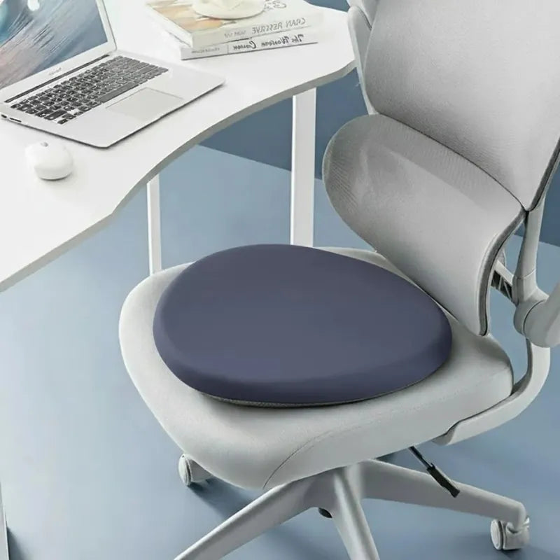 Coussin ergonomique rond bleu foncé sur une chaise de bureau ergonomique, apportant soutien et confort pendant le travail.