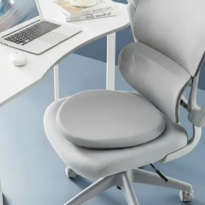 Coussin ergonomique rond gris installé sur une chaise de bureau, en mousse mémoire de forme, adapté à un environnement professionnel.