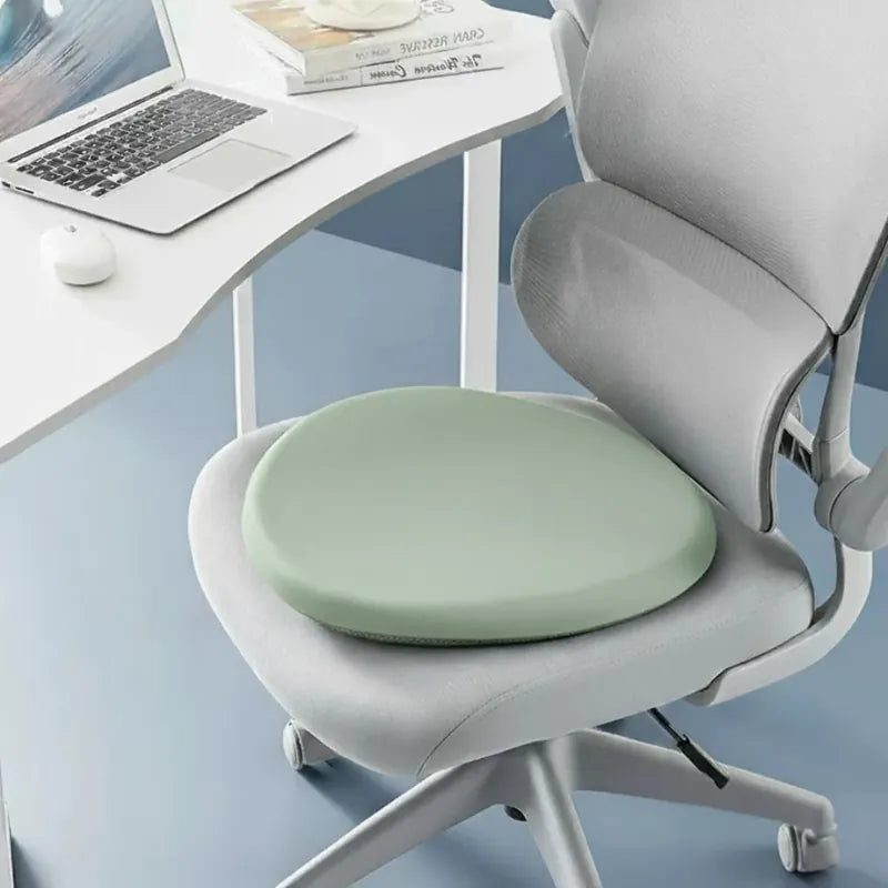 Coussin ergonomique rond vert clair posé sur une chaise de bureau ergonomique, idéal pour améliorer le confort d’assise et le maintien du dos durant le travail.