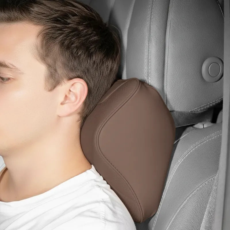 Homme assis dans une voiture appuyé sur un coussin ergonomique voiture set duo marron. Appui-tête et soutien lombaire en cuir synthétique posés sur un siège gris perle