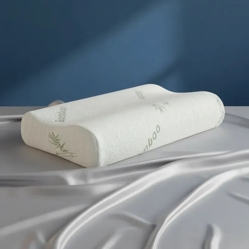 Oreiller à mémoire de forme bambou Blanc premium posé sur un drap satiné gris perle, avec un fond bleu uni
