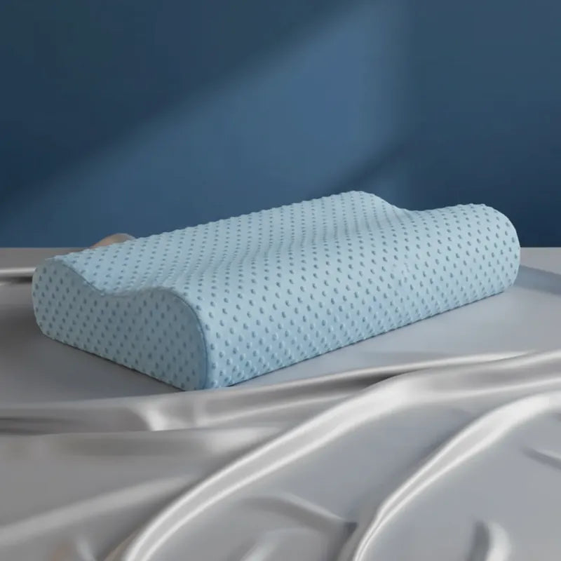 Oreiller à mémoire de forme bambou Bleu premium posé sur un drap satiné gris perle, avec un mur bleu en fond.