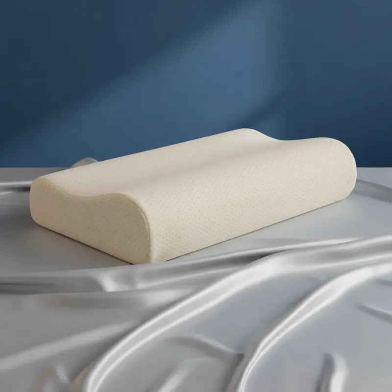 Oreiller à mémoire de forme bambou Jaune premium posé sur un drap satiné gris perle, devant un mur bleu.