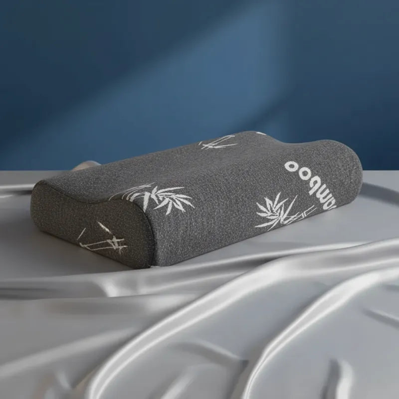 Oreiller à mémoire de forme bambou Noir premium reposant sur un drap satiné gris perle, avec un fond bleu.
