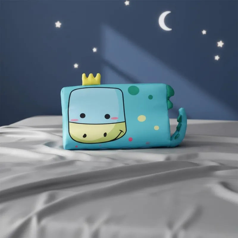 oreiller memoire de forme enfant dinosaure posé sur drap gris perle, mur bleu nuit avec étoiles et lune, ambiance rêve d’enfant