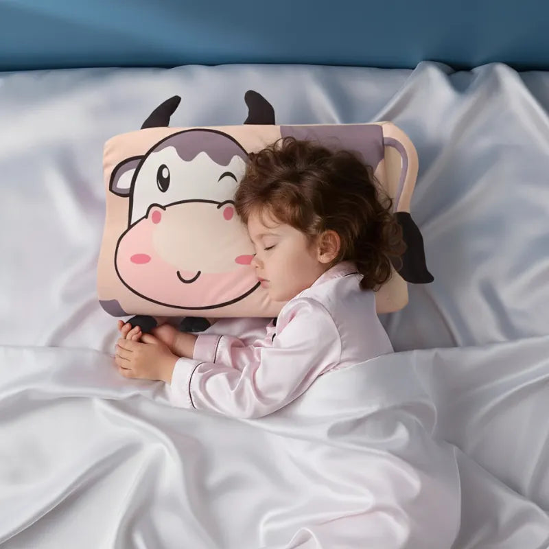 Enfant endormi paisiblement sur un oreiller mémoire de forme enfant vache dans une ambiance douce et premium.